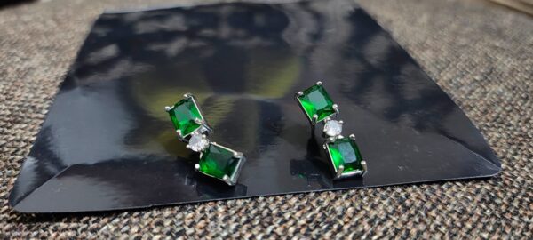 Green emerald stud earrings with cubic zirconia accents.