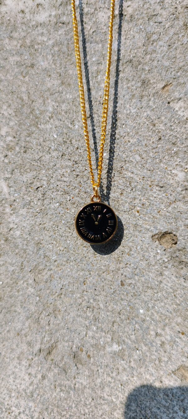 A necklace with a gold-toned chain and a circular clock pendant.