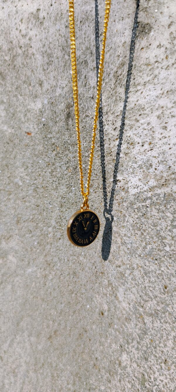 A necklace with a gold-toned chain and a circular clock pendant.