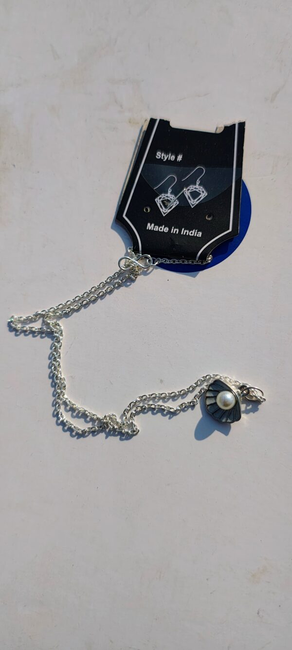 A necklace with a silver chain and a seashell pendant with a pearl.