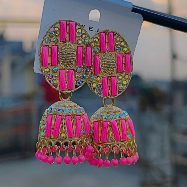 Elegant pink jhumka earrings with intricate detailing, sparkling embellishments, and a blend of traditional and modern design, displayed against a blurred outdoor background. Let me know if you want any tweaks!