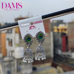 A pair of Peacock Feather Jhumka Earrings with oxidized silver detailing, peacock feather design, and hanging beads, displayed against an outdoor background.