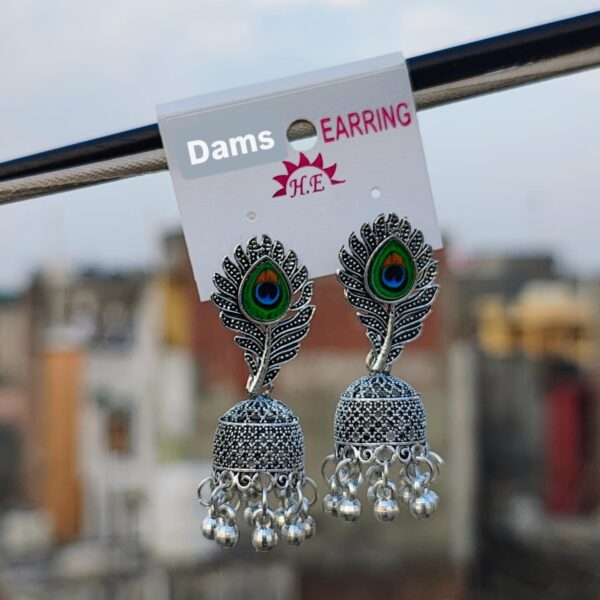 A pair of Peacock Feather Jhumka Earrings with oxidized silver detailing, peacock feather design, and hanging beads, displayed against an outdoor background.