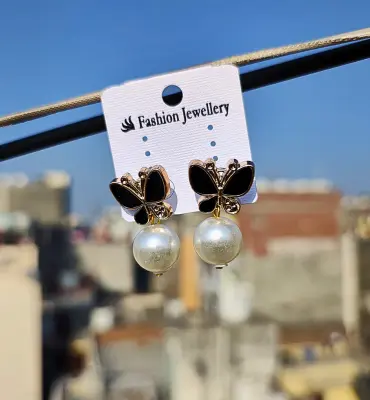 Black butterfly stud earrings with hanging white pearl drops, displayed on a fashion jewelry card
